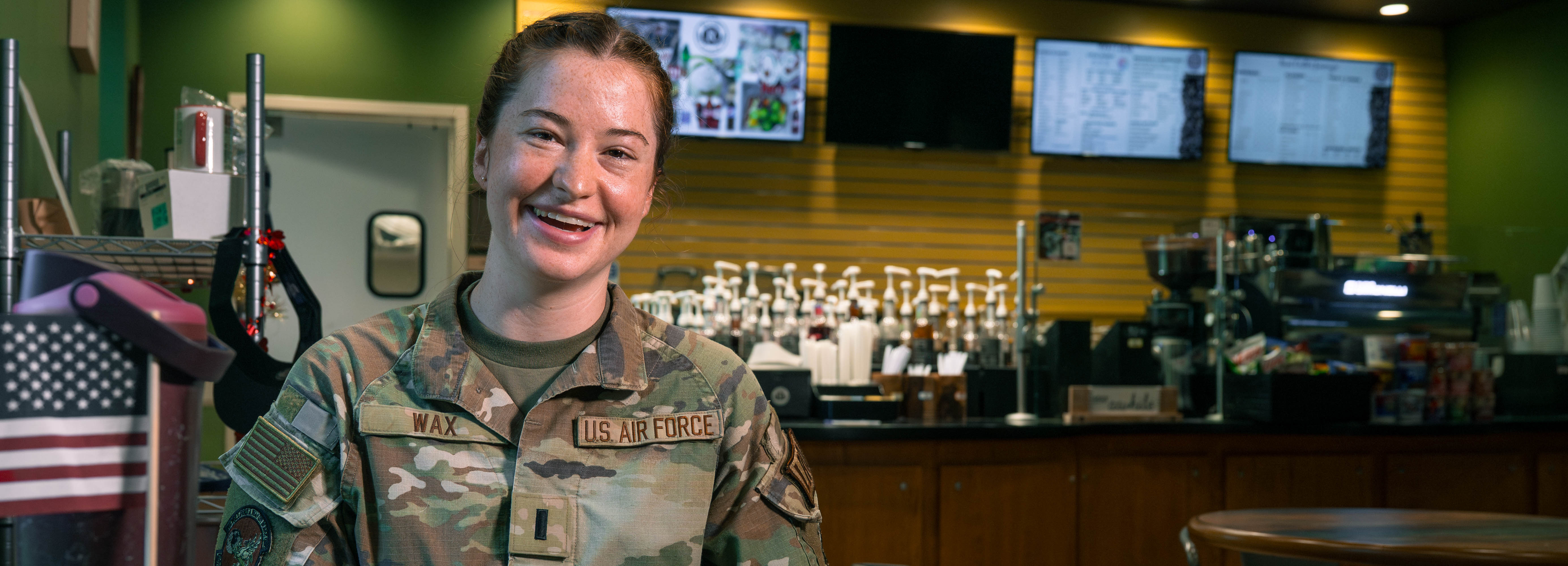  A photo of a service member smiling while sitting inside of a coffee shop.